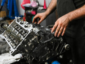 A mechanic is replacing a Kia engine, fitting a new gasket to the cylinder head in a workshop.